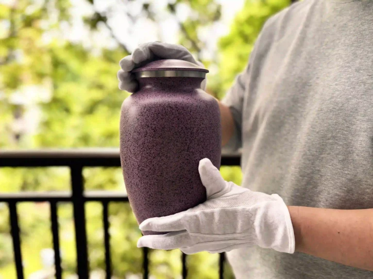 A pair of gloved hands performing a White Glove Inspection™ on a cremation urn