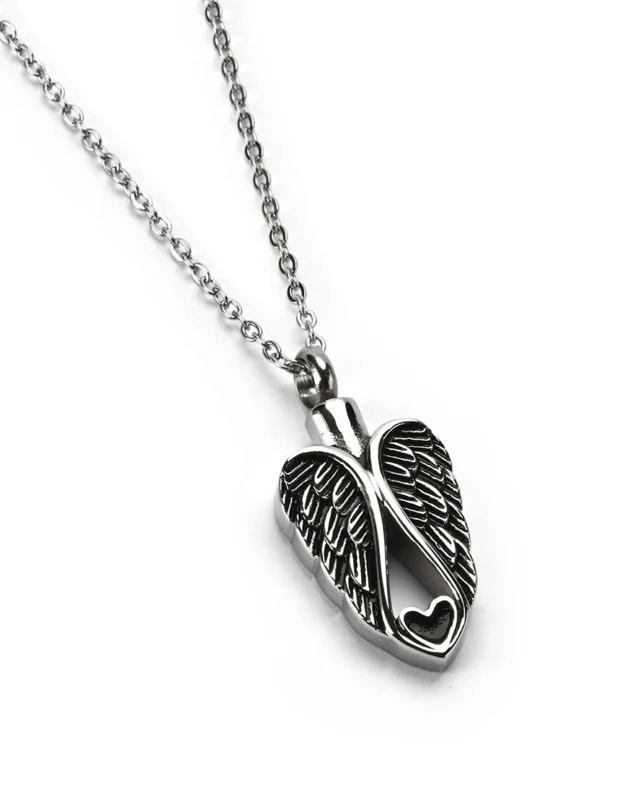 Angled view of angel wings heart cremation necklace for ashes in polished stainless steel with antiqued finish