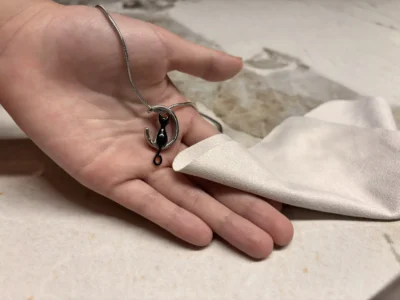 Home Main 22 Hands holding a cremation jewelry pendant and cleaning cloth during the filling process