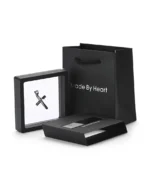 Twisted cross stainless steel necklace displayed in a floating presentation frame with gift bag