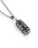 Angled view of Buddhist prayer wheel cremation necklace showing raised characters and ornamental detailing