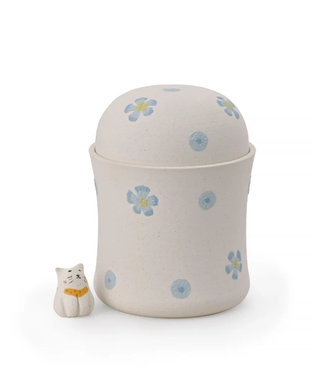Blue floral ceramic pet urn with a textured off-white surface, hand-painted flowers, dome-shaped lid, and separate cat figurine