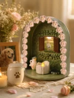 Green floral pet memorial shrine displaying a dog photo with pink flowers, LED candle, and paw-print urn nearby