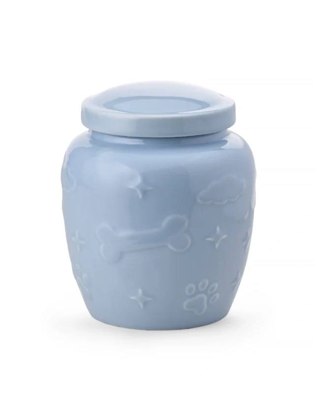 Light blue ceramic pet urn with glossy glaze, raised paw prints, bones, clouds, stars, and removable top lid