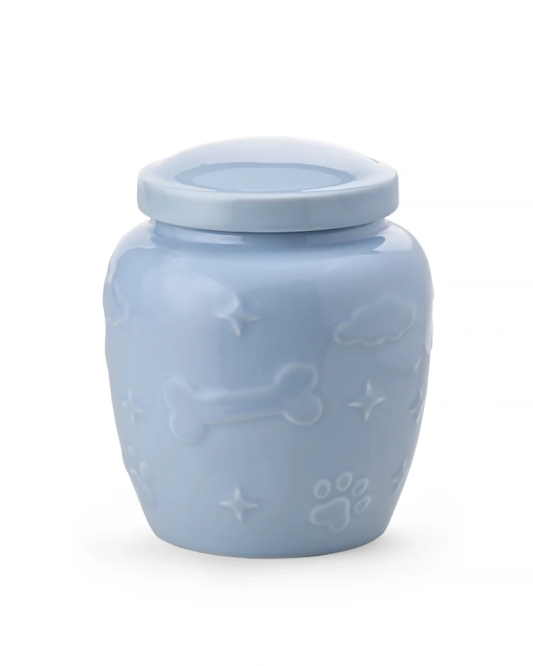 Light blue ceramic pet urn with glossy glaze, raised paw prints, bones, clouds, stars, and removable top lid